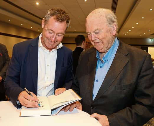 Former finance minister Michael Noonan gets his copy of Charlie vs Garret signed by Corbally-born academic and writer Eoin O’Malley | PICTURE: Adrian Butler