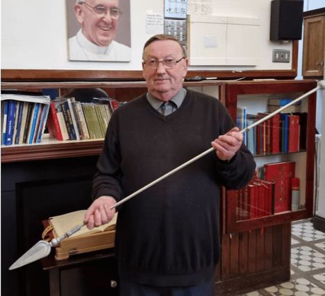 The late Fr Leo McDonnell holds the spear of the monument to Archangel Michael which he commissioned the repair of