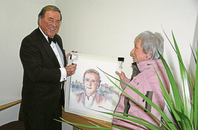 The late and great Terry Wogan signs a portrait by Barbara Hartigan, which is included in her collection of paintings of famous people that she is donating to charity