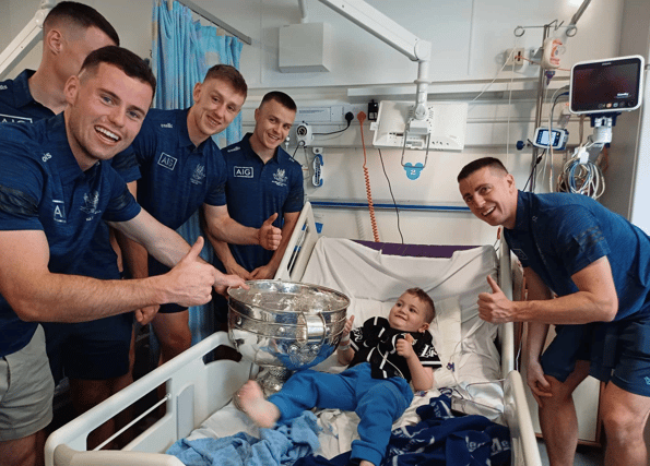 The Dublin footballers bring the Sam Maguire Cup to Noah Quish in hospital