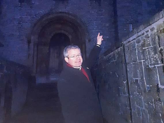 A light in the darkness: Dean Niall Sloane points up to the west window