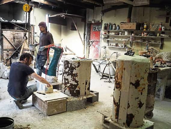 Sculptor Seamus Connolly, kneeling, working alongside Adam Pomeroy on the leg of the JFK statue