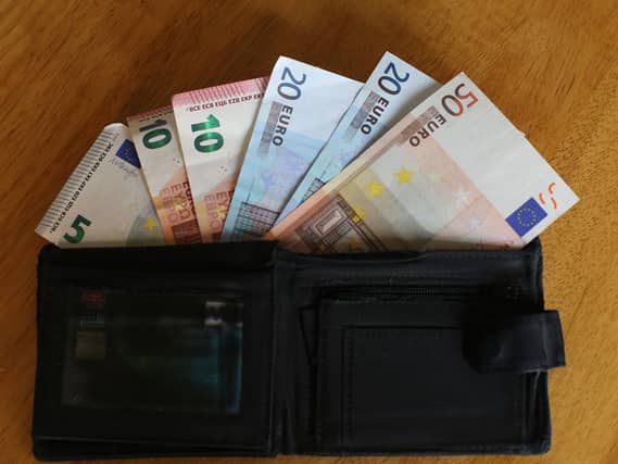 Euro notes sit inside a wallet