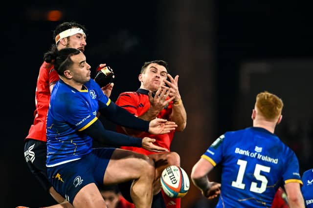 James Lowe of Leinster contests a high ball against Tom Ahern, left, and Tom Farrell of Munster during the United Rugby Championship match between Munster and Leinster at Thomond Park 2025