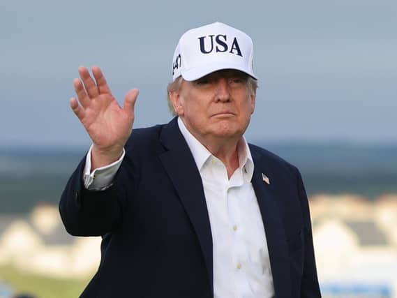 President Donald Trump waves while wearing a USA baseball cap at the Irish Open