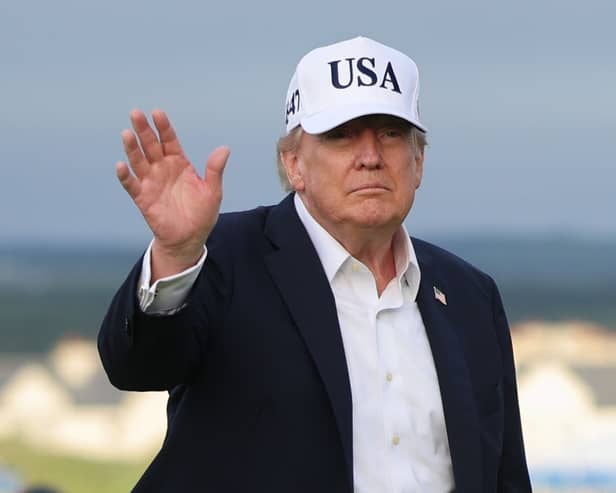 President Donald Trump waves while wearing a USA baseball cap at the Irish Open