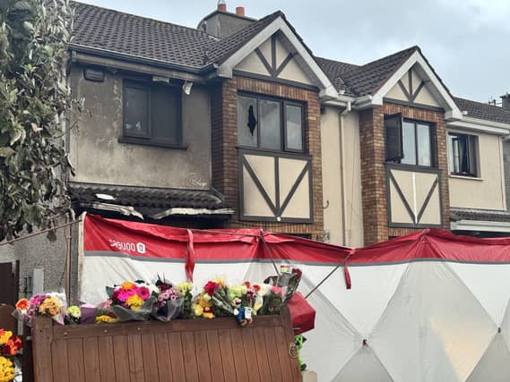 External view of a house showing signs of fire damage, with a forensic tent erected outside
