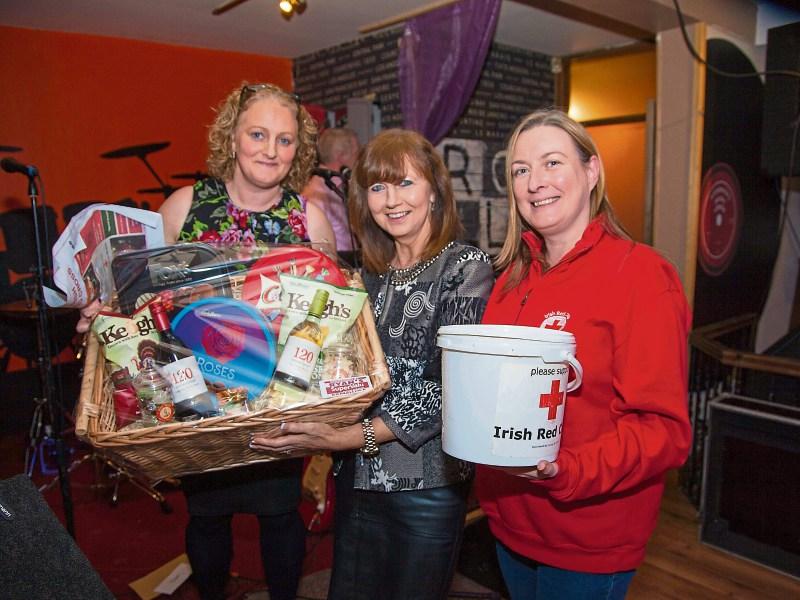 Annette Cleary Rees, Irish Red Cross, presenting a prize to Catherine Moloney at Fitzgerald's Bar with Kathryn Murphy, Irish Red Cross