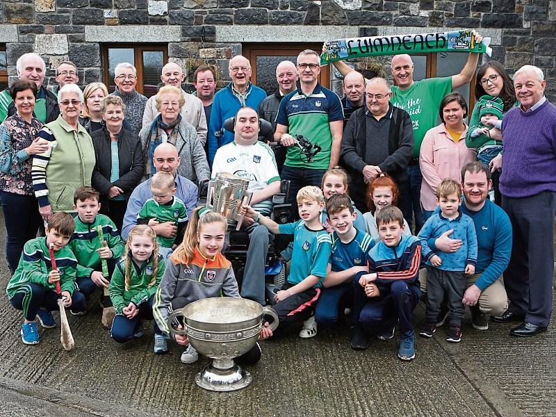 Fergal Cagney with his family, neighbours and friends and the Liam MacCarthy and Sam Maguire Cups outside his home in Kilteely Picture: Dave Gaynor