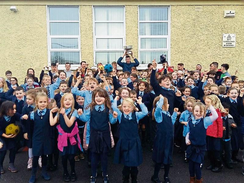 Goalkeeper Brendan Carmody holds the cup high as pupils at Adare’s Shountrade NS cheer on their team