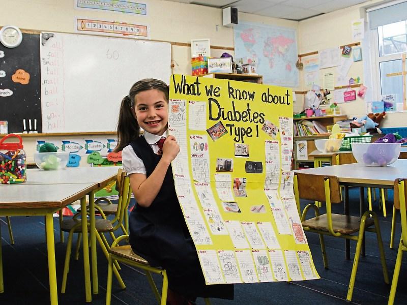 Ellie Noone, 7, proudly shows off the collaborative poster project she has completed in school