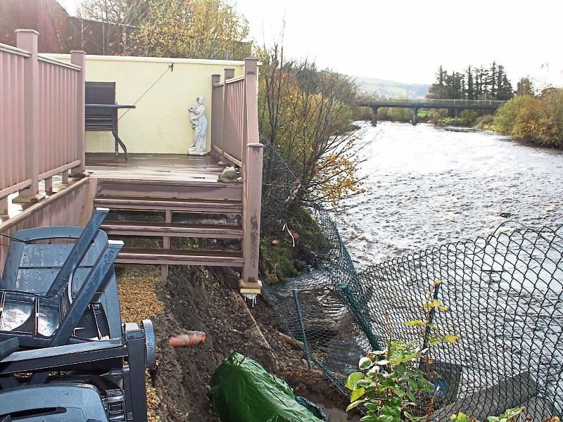 The rear of the Roches’ home  where a section of decking now hangs in mid-air and below, Cllr Liam Galvin left with Eamon and Marie Roche and Padraig Twomey Pictures: Michael Cowhey