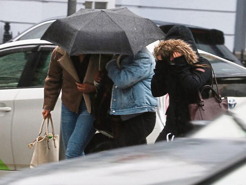Pedestrians take shelter under umbrella in Limerick this Tuesday during the poor weather Picture: Michael Cowhey