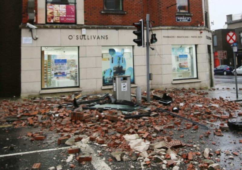 The portion of the front of this building collapsed on to the front of the car stopped at the light on Sarsfield Street (Picture: Liam Burke/Press 22) and below, O'Callaghan Strand is battered by high seas - picture from Twitter by Saara Kalliokoski