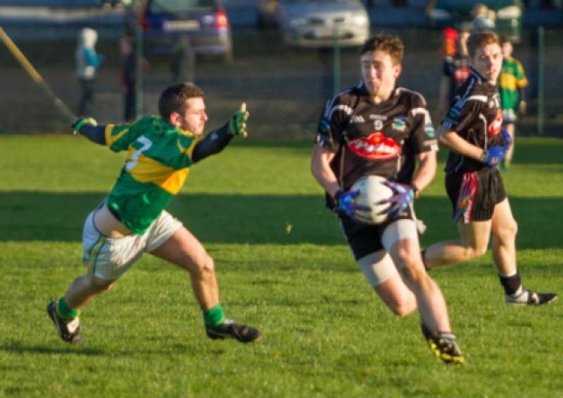 Newcastle West's Cian Sheehan takes the ball past the outstretched James Hough of St Kierans during their replay in the U-21 Football Championship semi-final in Tournafulla