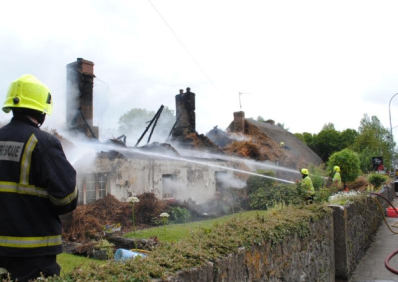 Fire service personnel fight the blaze at the thatched cottages in Adare at the weekend. Below, the late Willie and Mary Benson pictured at their cottage in 2012. Main Picture courtesy of Liam Woulfe
