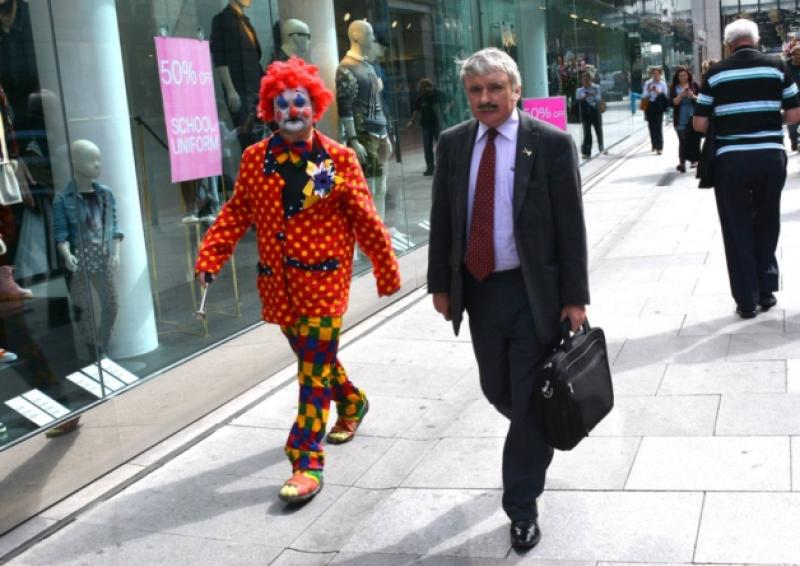 Looking glum: A colourful clown fails to turn Willie O'Dea's frown upside down after he left the Dail last week and was walking along Grafton Street